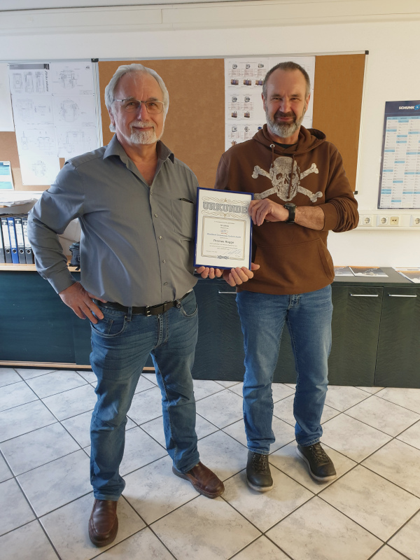 Thomas Rogge präsentiert seine Urkunde zum 10-jährigen Jubiläum als Mitarbeiter im Vertrieb für Drehmaschinen
